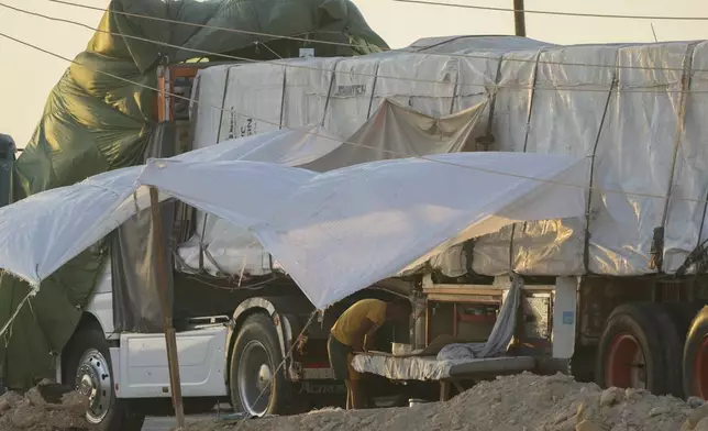 An Egyptian driver protects himself from sun at his truck of humanitarian aid as he waits to cross the Rafah border crossing between Egypt and the Gaza Strip, Monday, Sept. 9, 2024. (AP Photo/Amr Nabil)