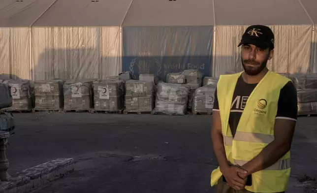 A worker stand near humanitarian aids at the logistic center near Rafah border crossing between Egypt and the Gaza Strip, Monday, Sept. 9, 2024. (AP Photo/Amr Nabil)