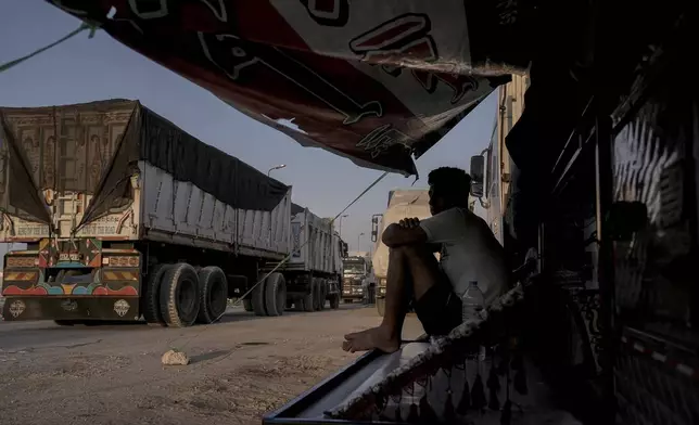 An Egyptian driver protects himself from sun on his truck of humanitarian aids as he waits to cross the Rafah border crossing between Egypt and the Gaza Strip in Rafah, Egypt, Monday, Sept. 9, 2024. (AP Photo/Amr Nabil)