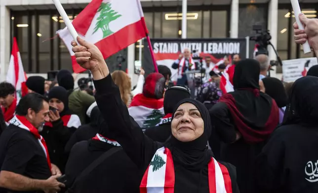 Najah Harb of Dearborn waves a Lebanese flag above her head as hundreds gather for a rally in support of Lebanon in light of recent Israeli strikes that killed hundreds, on Wednesday, Sept. 25, 2024 in front of the Henry Ford Centennial Library in Dearborn, Mich. (Katy Kildee/Detroit News via AP)