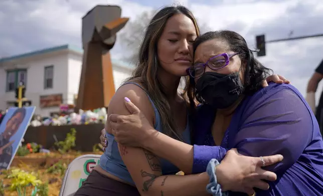 FILE - Community organizer Anthea Yur Kokoro, left, hugs Del Shea Perry, mother of Hardel Sherrell, who died while in police custody, during a rally at the site where George Floyd was killed, in Minneapolis on Sunday, April 18, 2021. (AP Photo/Julio Cortez, File)