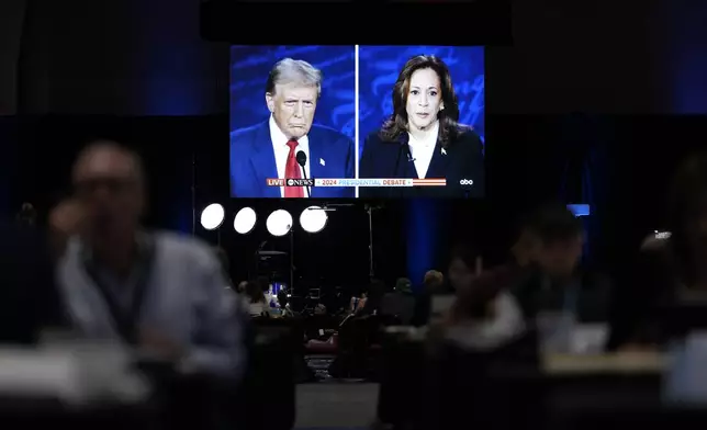 Members of the press appear in the spin room during a presidential debate between Republican presidential nominee former President Donald Trump, on screen at left, and Democratic presidential nominee Vice President Kamala Harris, right, Tuesday, Sept. 10, 2024, in Philadelphia. (AP Photo/Matt Slocum)