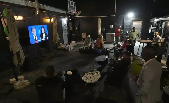 Patrons at the Knotty Luxe Bistro watch the presidential debate between Republican presidential nominee former President Donald Trump and Democratic presidential nominee Vice President Kamala Harris on an outdoor television Tuesday, Sept. 10, 2024, in Markham, Ill. (AP Photo/Charles Rex Arbogast)