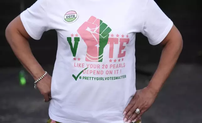 Natasha Salas, 63, from Highland, Ind., sports her pink and green t-shirt as she stands for a portrait outside the Knotty Luxe Bistro for an Alpha Kappa Alpha sorority debate watch party Tuesday, Sept. 10, 2024, in Markham, Ill. (AP Photo/Charles Rex Arbogast)