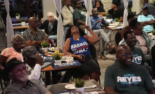 Teacher Elmire Desrouleaux of North Miami, center, reacts during a presidential debate between Republican presidential nominee former President Donald Trump and Democratic presidential nominee Vice President Kamala Harris at a watch party organized by Democrats from Miami's Haitian-American community, Tuesday, Sept. 10, 2024, at Randy's Restaurant &amp; Lounge in Miami. (AP Photo/Rebecca Blackwell)