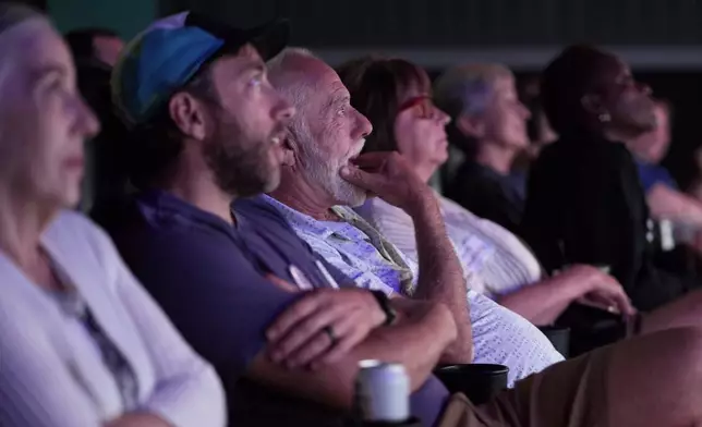 People watch the presidential debate between Republican presidential nominee former President Donald Trump and Democratic presidential nominee Vice President Kamala Harris at a 97-year-old movie theater Tuesday, Sept. 10, 2024, in Shawnee, Kan. (AP Photo/Charlie Riedel)