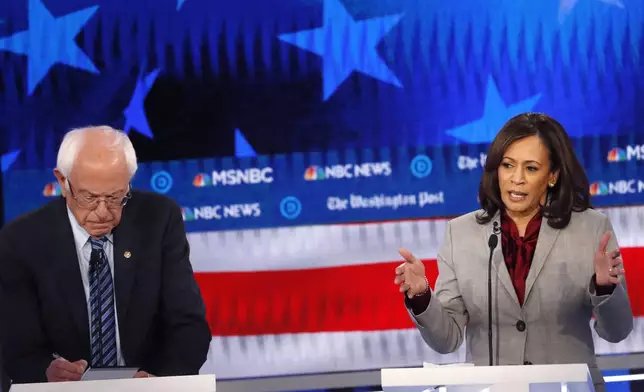 FILE - Democratic presidential candidate Sen. Kamala Harris, D-Calif., speaks as Democratic presidential candidate Sen. Bernie Sanders, I-Vt., takes notes during a Democratic presidential primary debate, Nov. 20, 2019, in Atlanta. (AP Photo/John Bazemore, File)