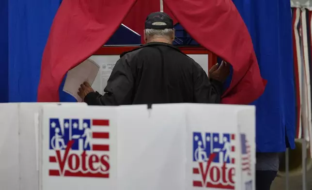 A voter enters a booth fill out a ballot in a primary election to pick candidates for governor, the U.S. House, and the state Legislature, Tuesday, Sept. 10, 2024, in Nashua, N.H. (AP Photo/Steven Senne)