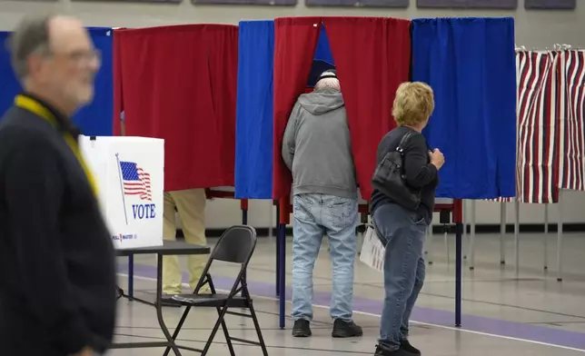 Voters, right, enter booths to fill out ballots Tuesday, Sept. 10, 2024, in Nashua, N.H., in a primary election to pick candidates for governor, the U.S. House, and the state Legislature. (AP Photo/Steven Senne)