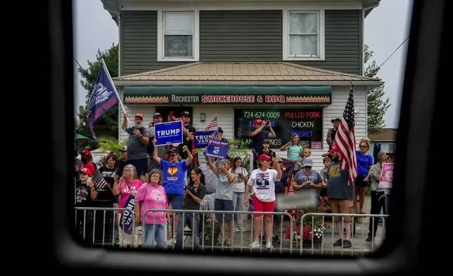 Supporters of Republican presidential nominee former President Donald Trump watch a campaign bus carrying Democratic presidential nominee Vice President Kamala Harris and her running mate Minnesota Gov. Tim Walz drive by, Sunday, Aug. 18, 2024, in Rochester, Pa. (AP Photo/Julia Nikhinson)