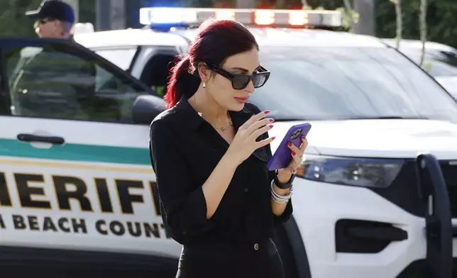 Laura Loomer uses her cell phone near Trump International Golf Club after police closed off the area following the apparent assassination attempt of Republican presidential nominee former President Donald Trump in West Palm Beach, Fla., Sunday, Sept. 15, 2024. (AP Photo/Terry Renna)