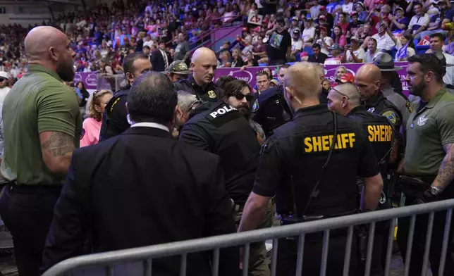 Police remove a man, center with sunglasses, who had climbed onto the media riser, as Republican presidential nominee former President Donald Trump speaks at a campaign event, Friday, Aug. 30, 2024, in Johnstown, Pa. (AP Photo/Alex Brandon)