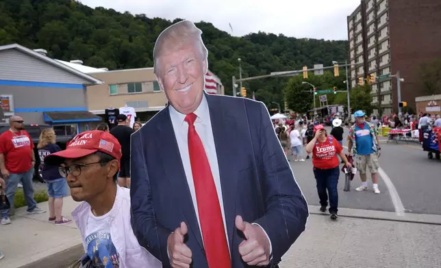 A person carries a cardboard cutout of Republican presidential nominee former President Donald Trump before a Trump campaign event, Friday, Aug. 30, 2024, in Johnstown, Pa. (AP Photo/Alex Brandon)