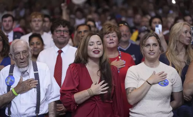 Audience members stand to say the Pledge of Allegiance before Republican presidential candidate former President Donald Trump arrives to deliver remarks on the tax code, and manufacturing at the Johnny Mercer Theatre Civic Center, Tuesday, Sept. 24, 2024, in Savannah, Ga. (AP Photo/Evan Vucci)