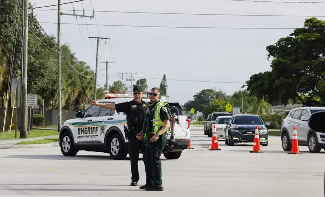 Police officers direct traffic near Trump International Golf Club after the apparent assassination attempt of Republican presidential nominee former President Donald Trump in West Palm Beach, Fla., Sunday, Sept. 15, 2024. (AP Photo/Terry Renna)