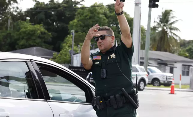 A police officer directs traffic near Trump International Golf Club after the apparent assassination attempt of Republican presidential nominee former President Donald Trump in West Palm Beach, Fla., Sunday, Sept. 15, 2024. (AP Photo/Terry Renna)