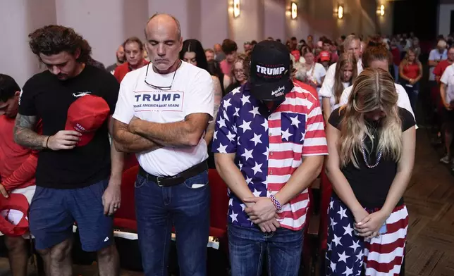 Audience members stand and pray before Republican presidential candidate former President Donald Trump arrives to deliver remarks on the tax code, and manufacturing at the Johnny Mercer Theatre Civic Center, Tuesday, Sept. 24, 2024, in Savannah, Ga. (AP Photo/Evan Vucci)