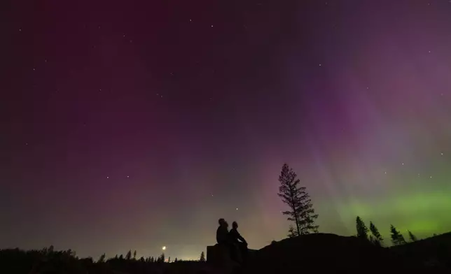 FILE - In this image taken with a long exposure, people look at the night sky towards the northern lights, or Aurora Borealis, May 10, 2024, in Estacada, Ore. (AP Photo/Jenny Kane, File)