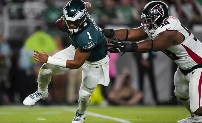 Philadelphia Eagles quarterback Jalen Hurts (1) runs past Atlanta Falcons defensive tackle David Onyemata (90) during the first half of an NFL football game Monday, Sept. 16, 2024, in Philadelphia. (AP Photo/Matt Slocum)