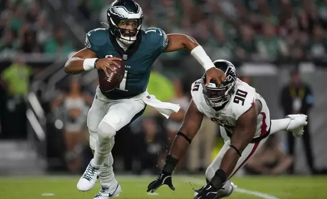 Philadelphia Eagles quarterback Jalen Hurts (1) runs past Atlanta Falcons defensive tackle David Onyemata (90) during the first half of an NFL football game Monday, Sept. 16, 2024, in Philadelphia. (AP Photo/Matt Slocum)