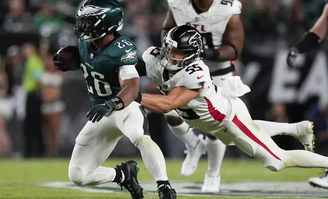 Philadelphia Eagles running back Saquon Barkley, left, is tackled by Atlanta Falcons linebacker Kaden Elliss (55) after a catch during the second half of an NFL football game Monday, Sept. 16, 2024, in Philadelphia. (AP Photo/Matt Slocum)