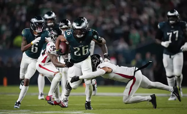 Philadelphia Eagles running back Saquon Barkley (26) runs with the ball under pressure from Atlanta Falcons cornerback A.J. Terrell (24) and Atlanta Falcons safety Jessie Bates III during the second half of an NFL football game on Monday, Sept. 16, 2024, in Philadelphia. (AP Photo/Matt Slocum)