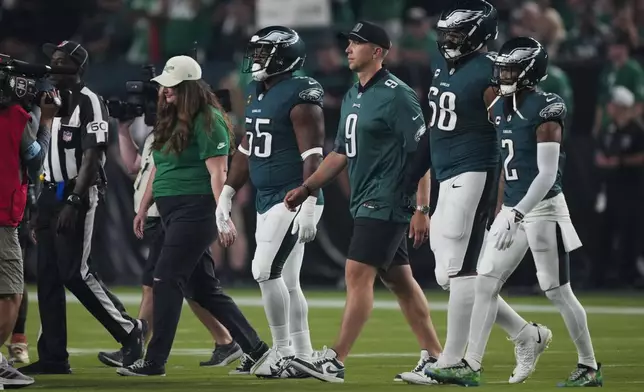 Former Philadelphia Eagles' Nick Foles, third from right, walks with Philadelphia Eagles' Brandon Graham, from left, Jordan Mailata and Darius Slay Jr. as they honor Foles' retirement before an NFL football game against the Atlanta Falcons on Monday, Sept. 16, 2024, in Philadelphia. (AP Photo/Matt Rourke)