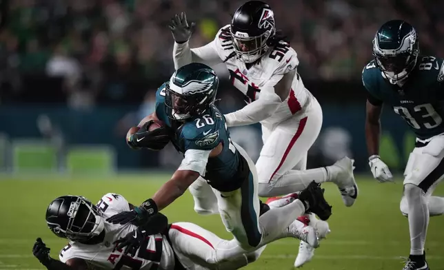 Philadelphia Eagles running back Saquon Barkley (26) falls with the ball near Atlanta Falcons cornerback Clark Phillips III, bottom, and Atlanta Falcons defensive end James Smith-Williams during the second half of an NFL football game Monday, Sept. 16, 2024, in Philadelphia. (AP Photo/Matt Slocum)