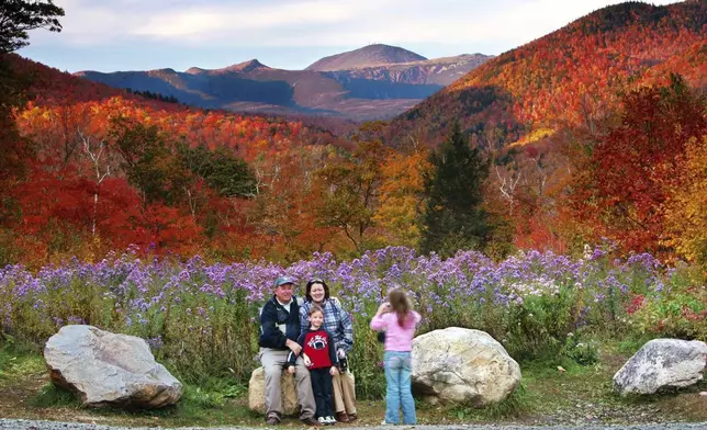 FILE - Wildflowers, fall foliage and the 6,288-foot Mt. Washington serve as a backdrop for Jim and Kathleen Gannon and their son James as their daughter Katarina snaps a picture at Crawford Notch State Park in New Hampshire, Oct. 6, 2006. (AP Photo/Robert F. Bukaty, File)