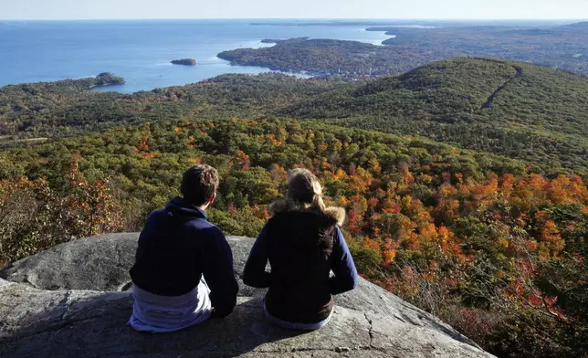 FILE - A couple takes in the view from the ocean lookout ledges of Mount Megunticook at Camden Hills State Park in Camden, Maine, on Oct. 12, 2009. (AP Photo/Robert F. Bukaty, File)