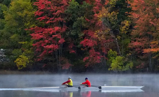 FILE - A pair of rowers glide on the Androscoggin River in Brunswick, Maine, where the foliage has changed to autumn colors, Oct. 10, 2021. (AP Photo/Robert F. Bukaty, File)