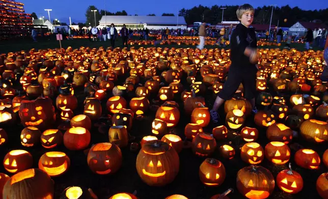 FILE - A boy finishes lighting a patch of jack-o-lanterns at the Camp Sunshine Maine Pumpkin Festival, Oct. 4, 2008, in Cumberland, Maine. (AP Photo/Robert F. Bukaty, File)