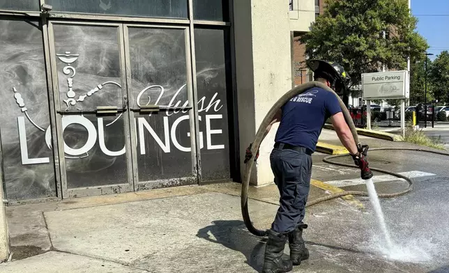 A firefighter cleans blood stains off the sidewalk outside a nightclub in Birmingham, Ala. on Sunday, Sept. 22, 2024, after a mass shooting took place. (AP Photo/Kim Chandler)