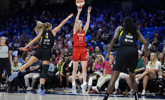 Indiana Fever guard Caitlin Clark (22) shoots as Dallas Wings' Jacy Sheldon (4) and Natasha Howard, right, defend in the first half of a WNBA basketball game Sunday, Sept. 1, 2024, in Arlington, Texas. (AP Photo/Tony Gutierrez)