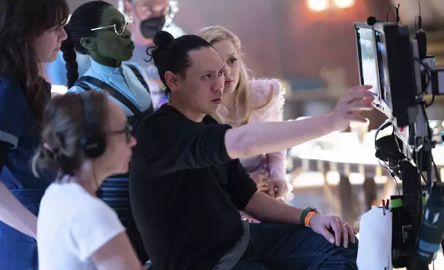 This image released by Universal Pictures shows director Jon M. Chu, center, on the set of "Wicked." (Giles Keyte/Universal Pictures via AP)