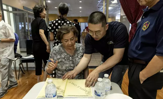 Cizhuo Cheng, field manager for One APIA Nevada, reviews a sample ballot with Sue Deng during the annual Dragon Boat Festival in Las Vegas on Wednesday, June 5, 2024. (Christopher Lomahquahu/News21 via AP)