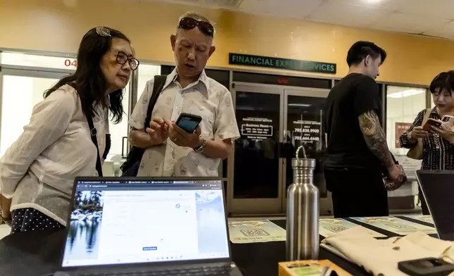 Members of the Las Vegas Asian community scan a QR code taking them to voter information translated into Chinese during the annual Dragon Boat Festival in Las Vegas, Wednesday, June 5, 2024. (Christopher Lomahquahu/News21 via AP)