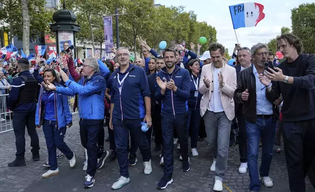 French President of the Paris 2024 Olympics and Paralympics Organising Committee (COJO) Tony Estanguet, center, walks down the Champs Elysees avenue on the day of a parade for all the French athletes who participated in the 2024 Olympics and Paralympics, Saturday, Sept. 14, 2024 in Paris.(AP Photo/Aurelien Morissard, Pool)