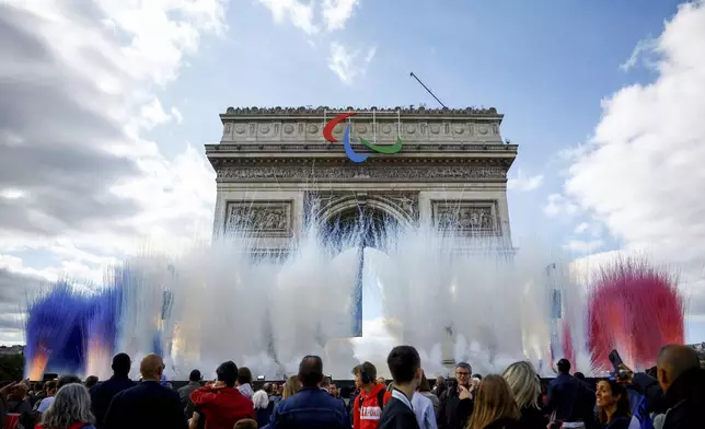 Smoke in colours of the French national flag rises near the Arc de Triomphe on the day of a parade for all the French athletes who participated in the 2024 Olympics and Paralympics, Saturday, Sept. 14, 2024 in Paris. (Sarah Meyssonnier, Pool via AP)