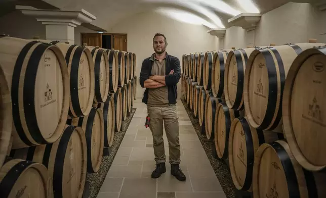 Arnaud Lavantureux, 35, co-owner of Domaine Lavantureux, is photographed between barrels of Chardonay wine in the cellar of the property, in Chablis, Burgundy region, France, Wednesday, Sept. 25, 2024. (AP Photo/Aurelien Morissard)