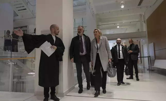 French far-right leader Marine Le Pen, center, arrives with her legal team at the court house in Paris, Monday, Sept. 30, 2024. (AP Photo/Thibault Camus)