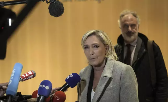 French far-right leader Marine Le Pen, front, speaks to the media as she arrives at the court house in Paris, Monday, Sept. 30, 2024. (AP Photo/Thibault Camus)