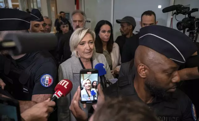 French far-right leader Marine Le Pen, front center, is flanked by police officers as she arrives at the court house in Paris, Monday, Sept. 30, 2024. (AP Photo/Louise Delmotte)