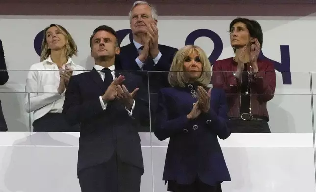 FILE - French Prime Minister Michel Barnier, background center, French President Emmanuel Macron, foreground left, and Macron's wife, Brigitte Macron, foreground right, applaud during the closing ceremony of the 2024 Paralympics, Sunday, Sept. 8, 2024, in Paris, France. (AP Photo/Michel Euler, File)