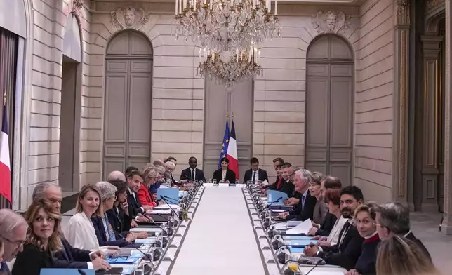 French President Emmanuel Macron, left, and Prime Minister Michel Barnier, right, meet with members of the new government during the weekly cabinet meeting at the Elysee Palace Monday, Sept. 23, 2024 in Paris. (AP Photo/Christophe Ena, Pool)