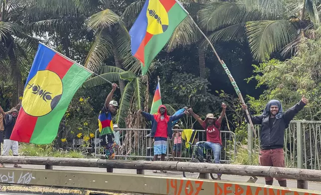 Indigenous Kanaks wave independent flags during the 171th anniversary of France's takeover of the Pacific Archipelago, in Noumea, New Caledonia, French Pacific islands, Tuesday Sept. 24, 2024. (AP Photo/Charlotte Antoine-Perron)