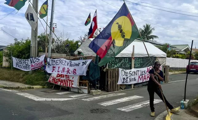 An indigenous Kanak holds the independent flag during the 171th anniversary of France's takeover of the Pacific Archipelago, in Noumea, New Caledonia, French Pacific islands, Tuesday Sept. 24, 2024. (AP Photo/Charlotte Antoine-Perron)