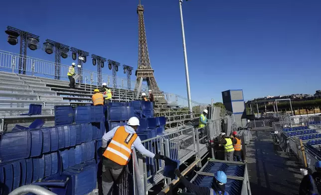 Workers remove grandstand seating as part of the dismantling of the Olympic venue the "Stade Tour Eiffel" with the Eiffel tower in the background in Paris, Friday, Sept. 13, 2024. (AP Photo/Michel Euler)