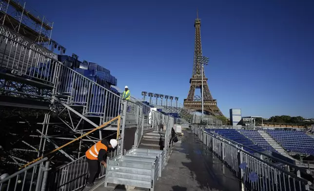 Workers remove grandstand seating as part of the dismantling of the Olympic venue the "Stade Tour Eiffel" with the Eiffel tower in the background in Paris, Friday, Sept. 13, 2024. (AP Photo/Michel Euler)