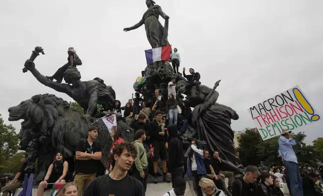 Demonstrators, one displaying French flag, gather under the statue of Marianne, a symbol of the French Republic, during a protest demonstration responding to a call from the far-left party leader who criticized as a power grab the president's appointment of a new prime minister, Michel Barnier, in Paris, France, Saturday, Sept. 7, 2024. (AP Photo/Michel Euler)